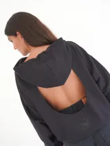 Buzo negro oversize de felpa con capucha y espalda descubierta, mangas largas, calce relajado y detalle de logo bordado en la parte inferior.