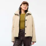 Campera de efecto borreguito en color beige, con cuello amplio y cierre frontal de botones negros. Presenta ribetes negros en contraste en el cuello, la apertura frontal y los puños. Marca Kiabi.