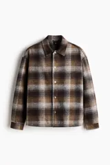 Sobrecamisa acolchada de corte relajado con diseño a cuadros en tonos marrones, grises y negros. Presenta cuello inglés, cierre frontal con botones a presión, hombros caídos y mangas largas con puños abotonados.