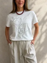 Remera gris melange de manga corta y cuello redondo, con estampado lineal negro de una flor en el frente.