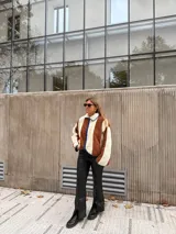 Campera de corderito con diseño de bloques de color, confeccionada en tejido sintético de textura suave. Presenta cierre frontal, cuello alto y ribetes en contraste en los bordes.
