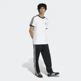 Pantalón deportivo Adidas Firebird de corte recto y holgado, color negro con las clásicas tres tiras blancas a lo largo de los laterales y el logo del trifolio bordado en la pierna izquierda.