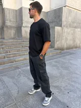 Pantalón cargo baggy negro gastado, con bolsillos laterales y un bolsillo tipo cargo en cada pierna.