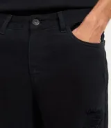 Bermuda masculina de sarga color beige con corte slim, diseño con roturas estilo destroyed y cierre tradicional de botón y cremallera.