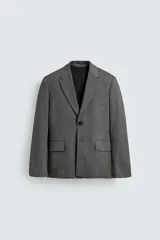 Blazer de corte boxy fit con estampado de espiga. Presenta cuello con solapas de muesca, cierre frontal de un botón, mangas largas con puños abotonados y bolsillos con solapa en la cadera.