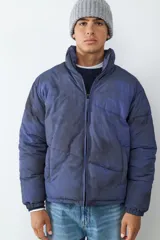 Campera acolchonada con efecto tie-dye en tonos azul y negro, cuello alto, cierre frontal con cremallera y bolsillos laterales. Cuenta con puños elásticos para mayor ajuste.
