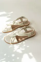 Sandalias chatitas de cuero en tono nude, con diseño de tiras cruzadas en el empeine y elástico en el talón para mayor ajuste. Presentan una plantilla acolchada y detalles en cuero charolado en la parte posterior.