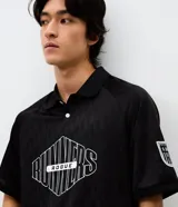 Polo de manga corta con cuello camisero y cierre frontal de botones. Presenta un diseño boxy fit con estampado gráfico en el pecho y detalle en la manga. Confeccionada en tejido técnico de microfibra.