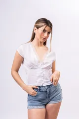 Blusa de lino liviano color blanco con textura plumeti, escote en V con detalle de encaje, botones frontales y mangas cortas.