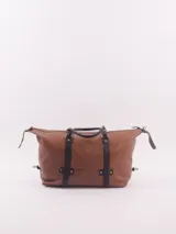Bolso de viaje tipo duffle, confeccionado en cuero natural color azul con textura, con detalles de correas y asas en cuero color suela. Cuenta con cierre superior, bolsillo interior con cierre y compartimento para celular.