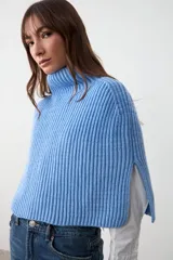 Capita tejida en punto acanalado color celeste, con cuello alto y aberturas laterales.