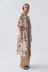 Kimono largo color crudo con estampado de hojas color camel, mangas tres cuartos y cinto para atar en la cintura.