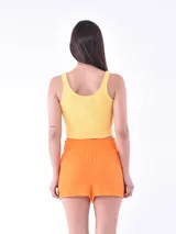 Short de tela liviana con textura plisada, color naranja, con cintura elástica alta tipo nido de abeja.