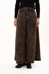 Pantalón de jean de tiro alto con corte wide leg y diseño de paneles verticales. Presenta un acabado lavado con efecto desgastado en tono chocolate, bolsillos funcionales y cierre frontal con botón metálico.