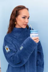 Buzo de peluche color azul, con cuello alto y diseño holgado. Presenta parches decorativos en las mangas.