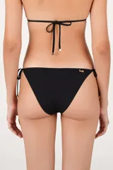 Calzón de bikini de tiro bajo color negro, con laterales de lazos ajustables con cuentas decorativas y una hilera de pequeños aros metálicos dorados en el borde superior.