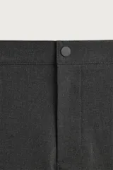 Pantalón de corte slim fit y color negro, confeccionado en tejido elástico. Cuenta con cintura elástica, trabillas, bolsillos frontales y cierre con cremallera y botón.