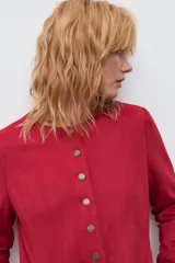 Chaqueta de textura simil gamuza en color rojo, con cuello redondo, cierre frontal mediante botones metálicos y bolsillos laterales.