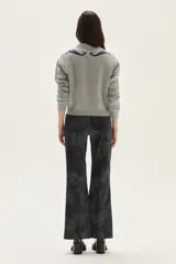 Sweater de tejido de punto color beige con diseño de arabescos en tonos marrones en hombros y mangas. Presenta cuello redondo con cordones decorativos y puños con textura acanalada.