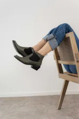 Botín negro de cuero con elásticos laterales, taco bajo y tirador trasero.