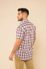 Camisa de manga corta con estampado de cuadros en tonos verdes, azules y blancos. Presenta cuello clásico, cierre frontal con botones y dos bolsillos delanteros con solapa.