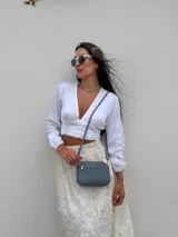 Bandolera pequeña de cuero sintético con textura granulada, cuenta con dos compartimentos con cierre y correa fina ajustable.