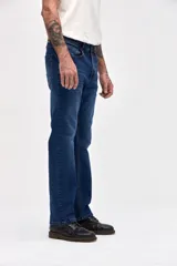 Jean de corte slim, ajustado desde la cadera hasta los tobillos, en color azul oscuro con costuras en contraste.