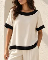 Blusa de manga corta color beige, con cuello redondo, dobladillo inferior y puños en color negro.