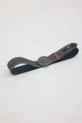 Cinturón de cuero color gris con efecto desgastado, hebilla metálica grande y redonda con diseño grabado, pasador marrón y tachas decorativas.