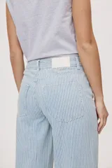 Pantalón wide leg de tiro medio con estampado de rayas verticales, diseño de cinco bolsillos, presillas para cinto y cierre frontal con botón y cremallera.