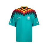 Camiseta de fútbol Adidas retro de la selección de Alemania, diseño alternativo de 1994. Color principal verde turquesa con cuello en V amarillo, rojo y negro, y un llamativo estampado geométrico en el pecho y las mangas en tonos negro, rojo y amarillo.