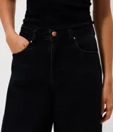 Pantalón de jean con corte barrel, de tiro medio y piernas anchas. Presenta un lavado marmorizado, trabillas en la cintura, cierre frontal con botón y cremallera, bolsillos funcionales y recortes decorativos en las rodillas.