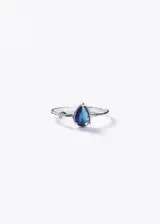 Anillo de plata 925 con piedra de zirconia en forma de gota de color azul y un pequeño punto de luz al lado.