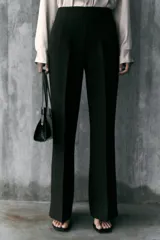Pantalón de tiro alto en color negro, con diseño de corte recto y ligeramente acampanado. Presenta costuras verticales marcadas en el frente y bolsillos laterales de vivo.