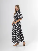 Conjunto de dos piezas con estampa polka dots en negro y blanco, compuesto por un pantalón tipo culotte de tiro alto con bolsillos y una blusa estilo camisa con mangas globo y cierre frontal de botones.