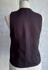 Chaleco negro con escote en V profundo y cierre frontal mediante lazos ajustables.