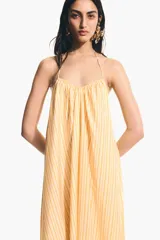 Vestido largo de corte holgado en tejido liviano, con diseño evasé, escote en V y breteles finos para atar en los hombros.