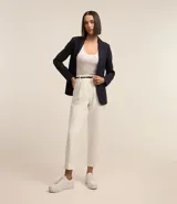 Pantalón carrot blanco de sastrería, con bolsillos laterales, pliegues frontales y cinturón fino negro con hebilla pequeña.