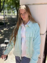 Campera corta de pana color violeta con cuello camisero, cierre frontal con botones dorados, bolsillos de parche en el pecho y corte recto.