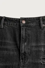 Jeans flare fit de denim de algodón negro con efecto desgastado, roturas, costuras decorativas en las perneras y bajo irregular deshilachado.
