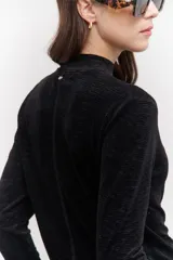 Polera de terciopelo color dorado, con cuello alto y mangas largas.