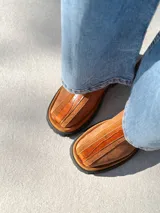 Botas cortas de cuero color marrón con elástico en los laterales y detalle de cuero texturizado en la parte delantera.