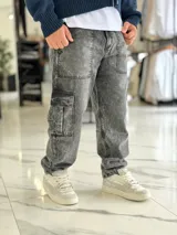 Pantalón cargo de jean azul claro, con bolsillos laterales tipo cargo en las piernas y bolsillos frontales aplicados, de corte ancho y holgado.