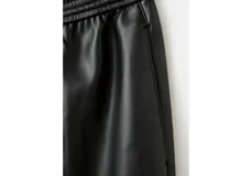 Pantalón de cuero sintético negro de corte recto, con cintura elástica ajustable mediante cordón y bolsillos laterales.