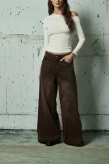 Jean de corte wide leg en color marrón oscuro, con diseño de tiro bajo y detalle de tachas metálicas a lo largo de las costuras laterales.
