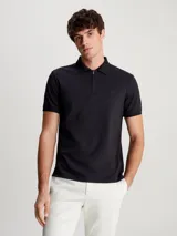 Chomba Calvin Klein negra de algodón, con cuello polo y media cremallera. Tiene mangas cortas y parche de goma con el logo de la marca en el pecho.