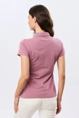 Remera polo de piqué color rosado, con mangas cortas, cuello clásico y cierre frontal de botones.