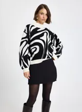 Sweater de punto con diseño estampado abstracto en blanco y negro, cuello alto, mangas largas y puños acanalados.