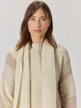 Bufanda de gran tamaño en color mostaza con diseño de tejido en espiga y flecos en los extremos. Incluye una etiqueta metálica decorativa en una de las esquinas.