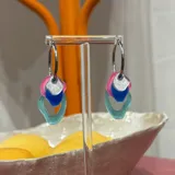 Aros colgantes con argolla plateada y tres piezas geométricas colgantes de acrílico en colores rosa, plateado, azul y celeste.